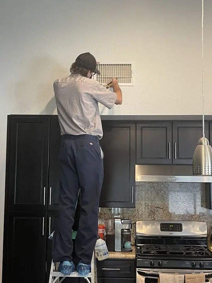 Technician inspecting an air vent during HVAC service in Aldine